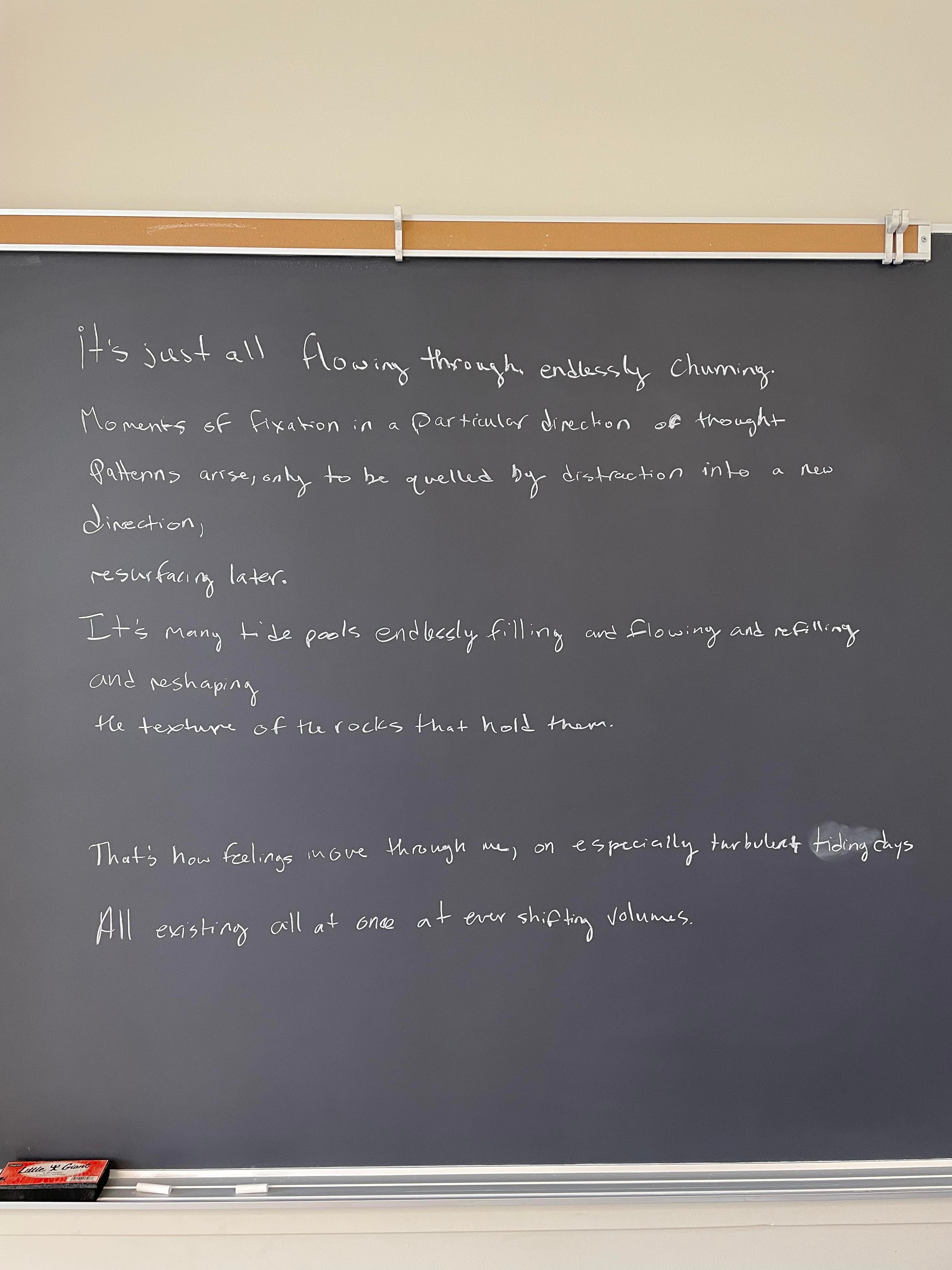 image of a classroom chalkboard with a poem written on it that reads "it's just all flowing through endlessly churning. moments of fixation on a particular direction of thought patterns arise, only to be quelled by distraction into new direction, resurfacing later. It's many tide pools filling and flowing and refilling and reshaping the texture of the rocks that hold them. That's how feelings move through me, on especially turbulent tiding days. All existing all at once at ever shifting volumes"
